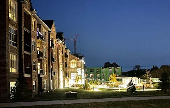 a row of apartment buildings at night with a park in the foreground