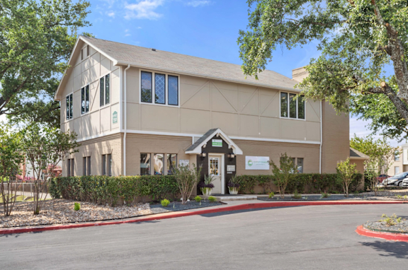 A beige building with a black roof and a sign on the front at Chevy Chase in Austin, 78752