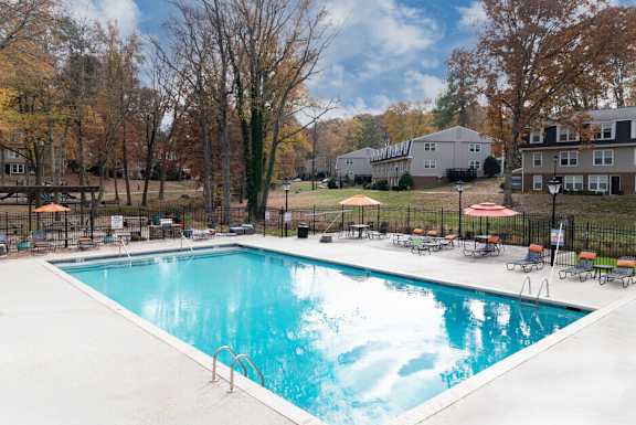 a pool with chairs and umbrellas next to a building