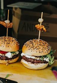 Three mini burgers with toppings are on a metal tray.