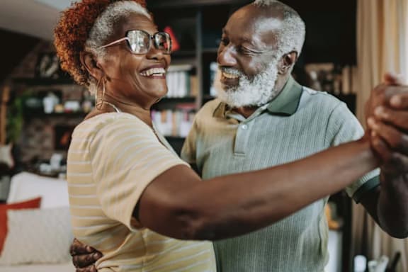 An elderly couple dancing together in a room.