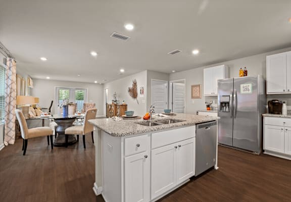 a white kitchen with a large island and a stainless steel refrigerator