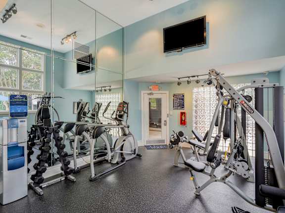 A gym with a row of exercise bikes and a television mounted on the wall.