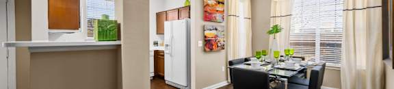 Spacious dining room with wood grain plank flooring, oversized windows, spacious kitchen with white appliances and side by-by-side refrigerators The Lanesborough Apartments in Houston.