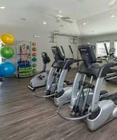 A gym with treadmills, elliptical machines, and other exercise equipment.
