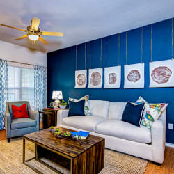 a living room with a blue accent wall and a white couch at Villa Espada Apartments, San Antonio, Texas