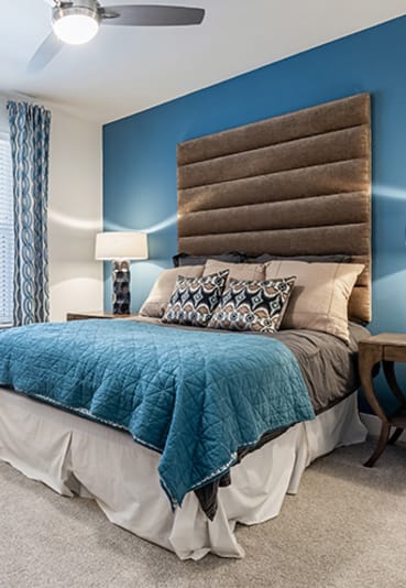 a bedroom with blue walls and a brown and blue headboard