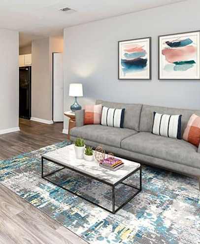 A living room with a grey couch, a coffee table, and a dining table with chairs. at Westbury Creek, Augusta, GA, 30909