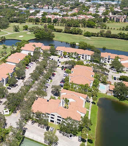 A golf course with a body of water and houses in the background.