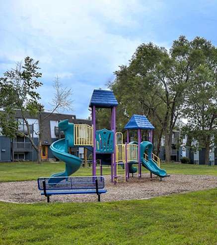 A playground with a green slide and a blue roof.