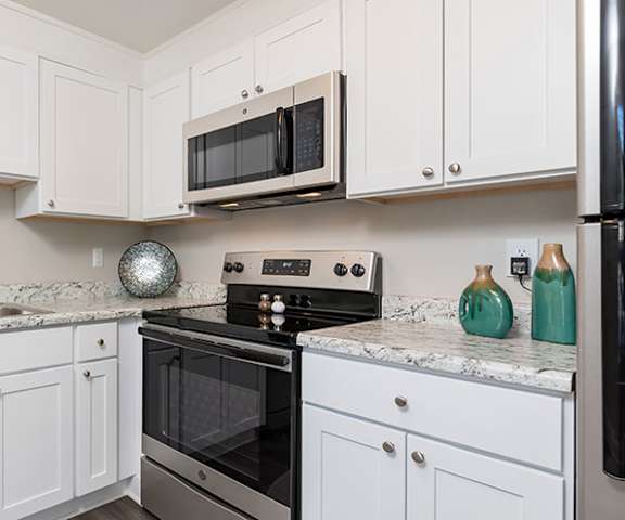A kitchen with white cabinets and black appliances.