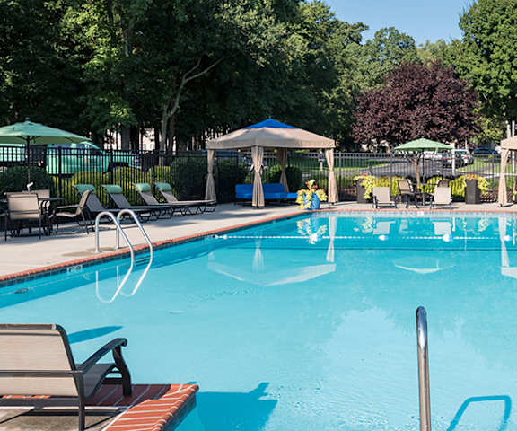 A large swimming pool with a fountain in the middle and sun loungers around the pool.