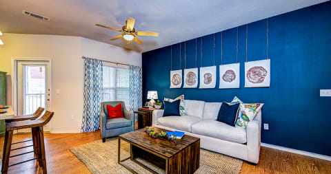 a living room with a blue accent wall and a white couch at Villa Espada Apartments, San Antonio, Texas