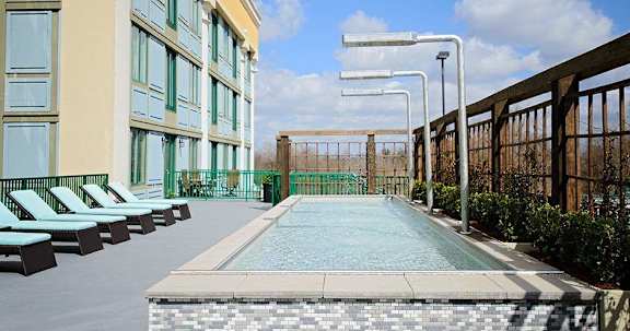 a swimming pool with chairs next to a building