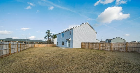 a backyard with a house and a wooden fence