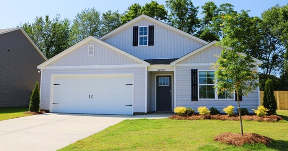 a white house with a garage door and a lawn