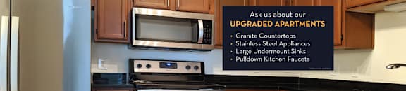 Luxury apartments with spacious kitchens, black granite countertops, stainless steel appliances, honey brown toned cabinets, and side-by-side refrigerators at The Lanesborough Apartments in Houston