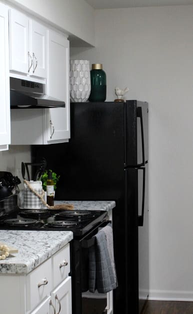 a kitchen with white cabinets and black appliances and granite counter tops
