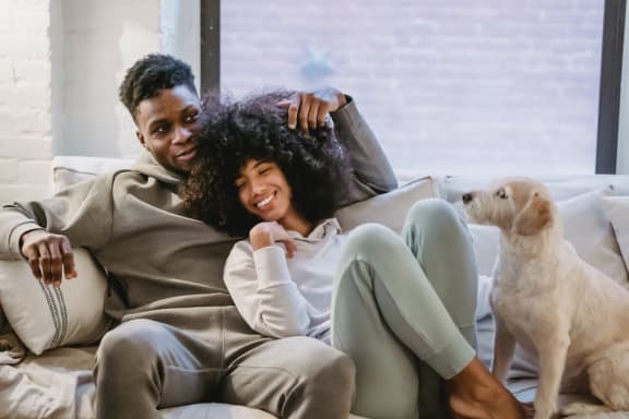 a couple sitting on a couch with a dog