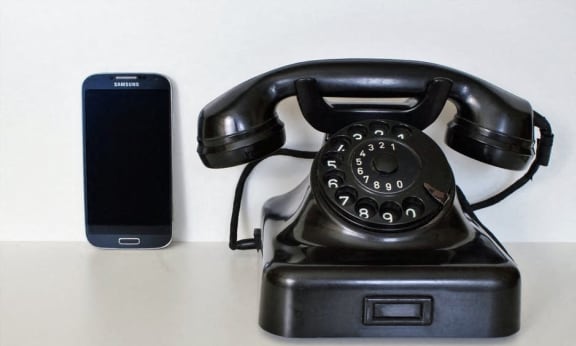 a black telephone sitting next to a cell phone