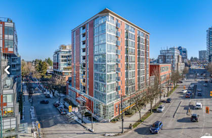 A tall red and white building is in the middle of a city street.