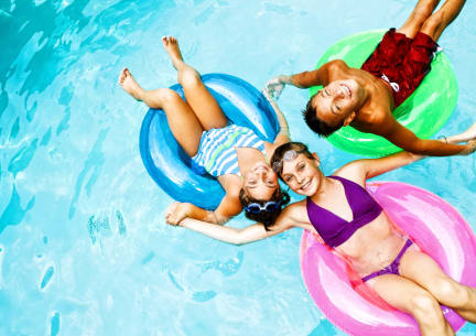 three people in a swimming pool on inflatable tubes