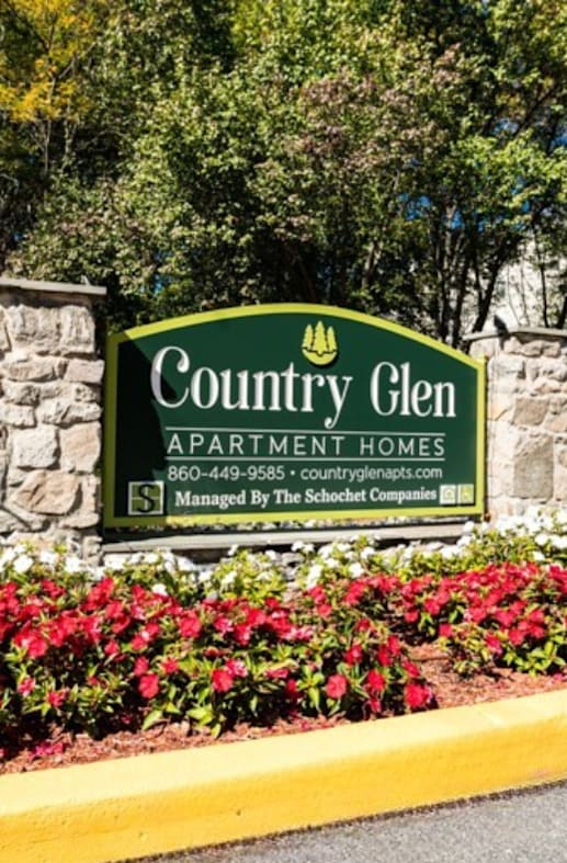 A sign for Country Glen Apartment Homes sits in front of a flower bed.