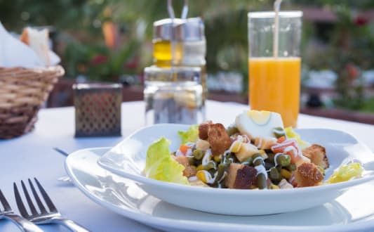 a plate of salad on a table with a glass of orange juice