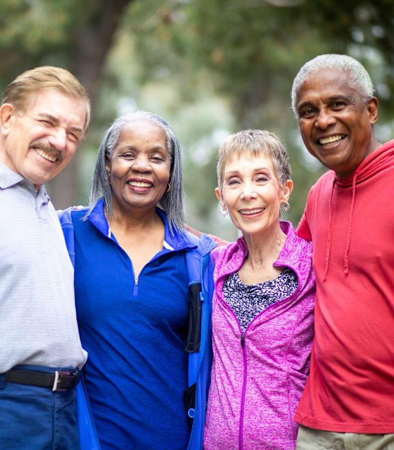 Four people standing together in a park.