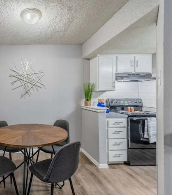 A kitchen with a table and chairs in the foreground and a stove in the background.
