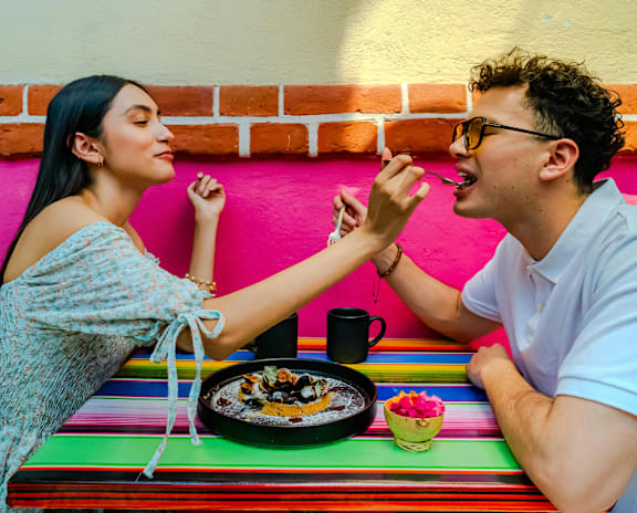 A man and woman sharing a meal at a colorful table.
