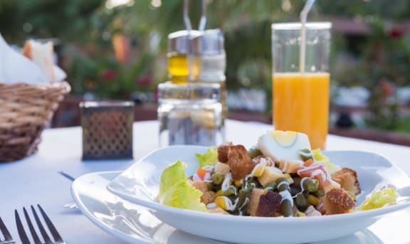 a plate of salad on a table with a glass of orange juice