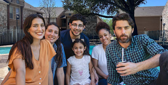 A group of people are sitting together outside on a sunny day.