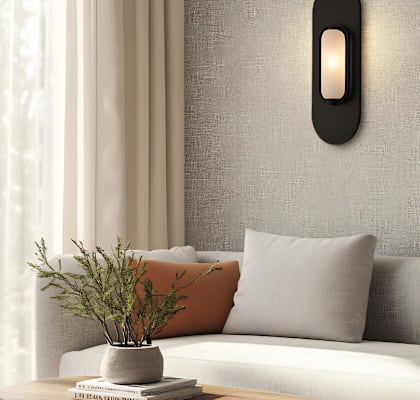 A modern living room with a grey sofa, a grey cushion, a grey pillow, a grey wall, a grey curtain, a grey table, a grey vase, a grey plant, a grey book, a grey wall
