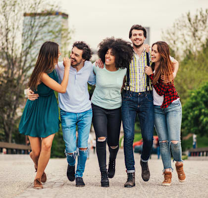 A group of five friends are walking together in a park.