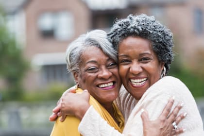 Two women hugging each other in front of a house.
