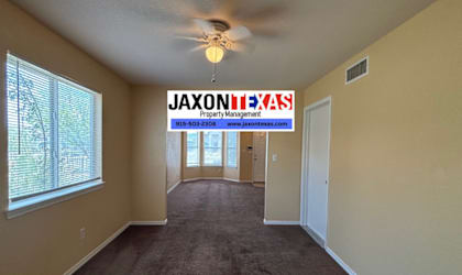 A room with a carpet floor and a ceiling fan.