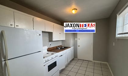 A kitchen with white appliances and cabinets with a JAXON B.A.S.S Property Management sign in the background.