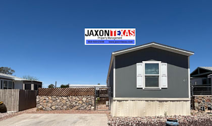 A grey house with a sign that says JAXONTEXAS in front of it.