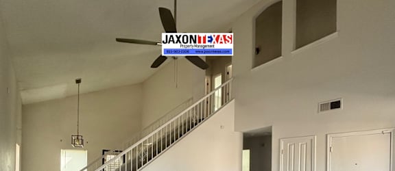 A spacious room with wooden flooring and a staircase leading to the upper level.