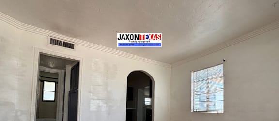 A room with wooden floors and a sign that says "Jaxontexas" on the wall.