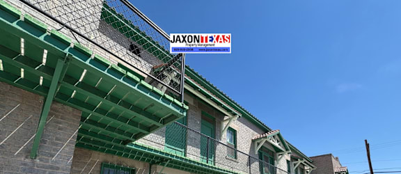 A building with a green awning and a sign that says "Jaxontexas" on it.