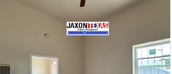 A room with a ceiling fan and a window showing a view of a street.