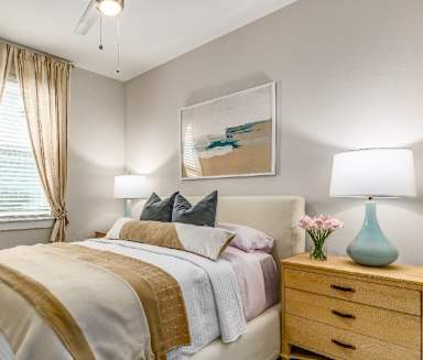 A bedroom with a bed, nightstand, and a painting on the wall.