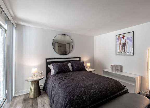 A bedroom with a large bed and a round mirror on the wall.
