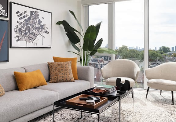 A living room with a grey couch, a coffee table, and a large window.