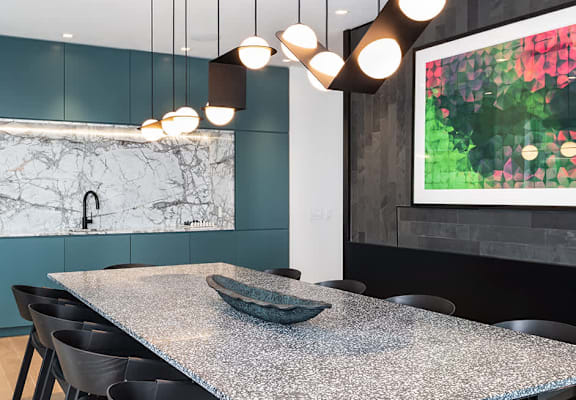 A modern dining room with a marble countertop and black chairs.