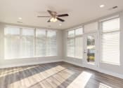 Thumbnail 32 of 48 - an empty living room with a ceiling fan and windows