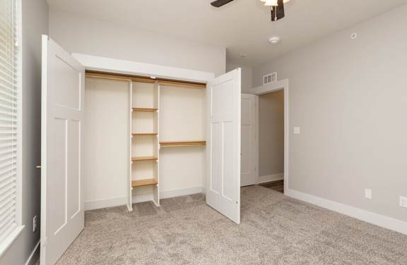 an empty bedroom with a closet and shelves