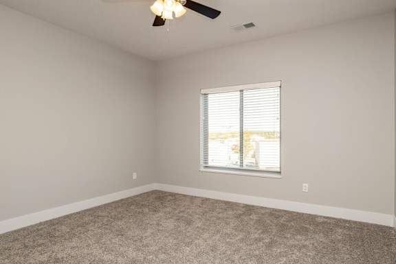 an empty room with a window and a ceiling fan